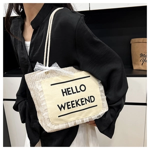 Detail of straw tote bag with HELLO WEEKEND text, lace edges and rope shoulder strap