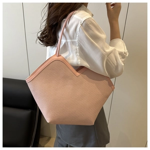 Detailed side view of large pink woven tote bag with leather straps on a model