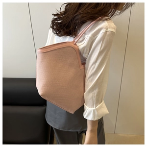 Pale pink woven straw tote bag with leather trim shown on model for elegant summer style