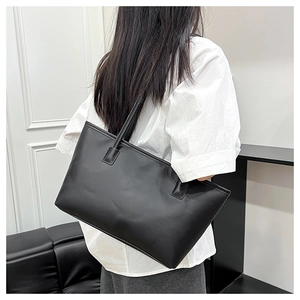 Minimalist black leather tote bag shown on shoulder for a size and drape perspective