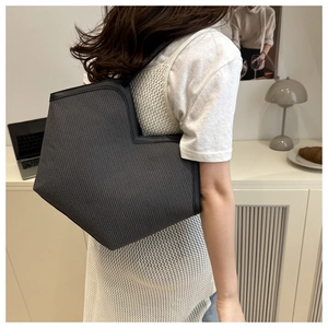 Detail of grey woven tote bag with unique V-cut opening and sleek black leather piping