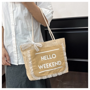 Close-up of woven straw tote bag featuring white lace trim and Hello Weekend print