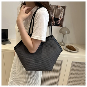 Detail of grey woven tote bag with slim black straps in a minimalist lifestyle setting