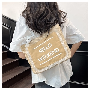 Detail of woven straw tote bag featuring Hello Weekend patch and white lace trim