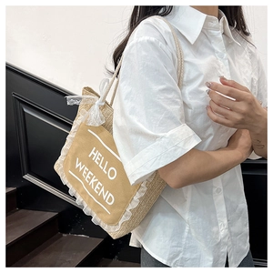 Detail of straw woven tote bag with Hello Weekend print and lace trim on model