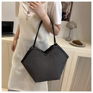 Detail of woven straw tote bag with V-shaped opening and slim black leather straps