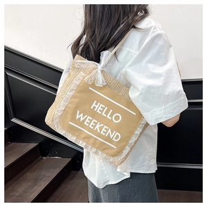 Detail of straw tote bag featuring lace-trimmed canvas pocket and Hello Weekend text
