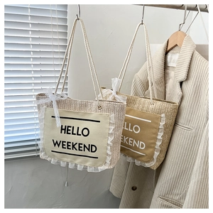 Detail of woven straw tote bag featuring Hello Weekend print and white lace trim
