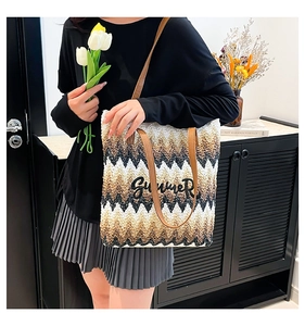 Detail of woven straw tote bag with Summer embroidery and leather handles on a model