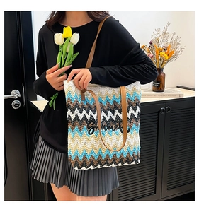 Detail of colorful woven straw tote bag with Summer embroidery and leather handles