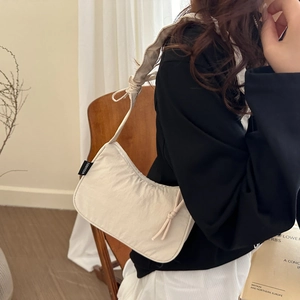 Minimalist beige crescent shoulder bag with knotted strap and light nylon texture