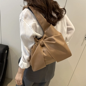 Brown tote bag with large bow decoration and minimalist shoulder strap design