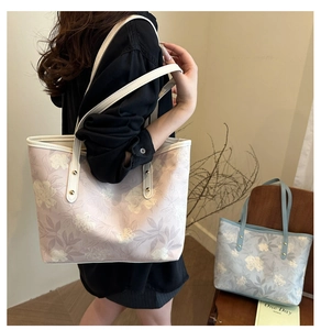 Detail view of pink floral print tote bag with white leather straps and gold rivets