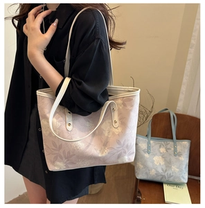 Detail of floral print canvas tote bags featuring leather straps and metal rivet reinforcement