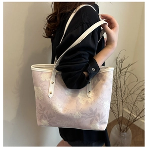 Detail of pink floral tote bag with white leather straps and golden rivet accents