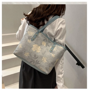 Detail of floral printed light blue canvas tote bag showing rivet strap attachment