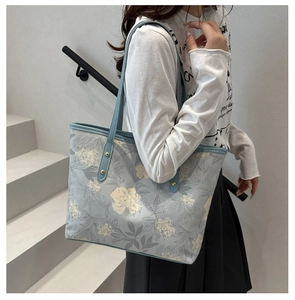 Detail of light blue floral tote bag with large flower patterns and reinforced straps