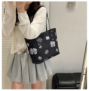 Mirror selfie showing the scale and drape of a black floral tote bag with leather straps