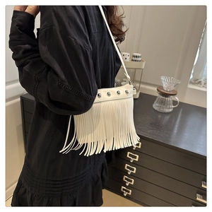 Detail shot of white tassel shoulder bag with silver rivets worn by a model