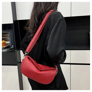 Detail of red lychee pattern leather crescent bag with golden metal buckle and wide strap