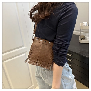 Détail du sac bandoulière en cuir PU marron avec clous argentés et longues franges
