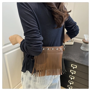 Detail view of brown leather bag with silver rivets, long tassels, and adjustable strap