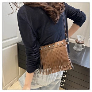 Détail du sac bandoulière marron avec des rivets argentés et de longues franges