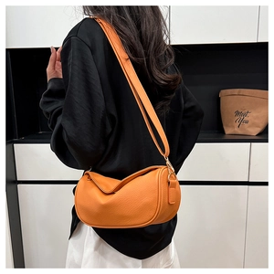 Detail of orange lychee textured leather crossbody bag with golden metal hooks