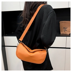 Detail of orange lychee leather crossbody bag with wide strap and golden hardware hooks