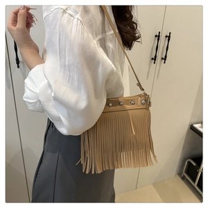 Detail of khaki leather tassel bag featuring silver studs and adjustable shoulder strap