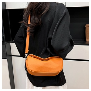 Detail of vibrant orange crescent crossbody bag with lychee texture and gold hardware