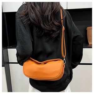 Detail of orange lychee leather crossbody bag with adjustable strap and gold metal clasp