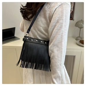Detail of black leather crossbody bag featuring silver studs and long fringe tassels