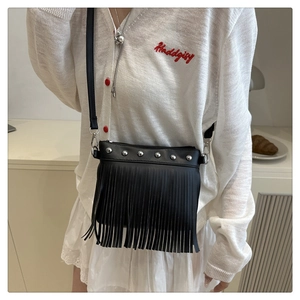 Detail of black bohemian tote bag featuring silver metal rivets and long fringe tassels