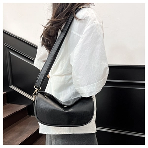 Detail of black pebbled leather half-moon crossbody bag with adjustable wide strap