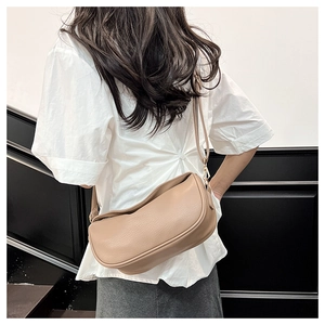 Detail shot of beige crescent crossbody bag showing pebbled leather texture and gold hardware