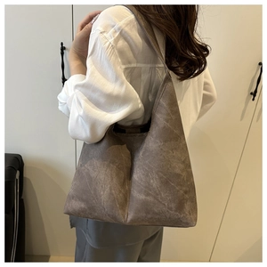 Close-up of vintage brown tote bag showing textured matte leather and minimalist stitching