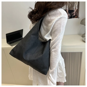 Detailed back view of a large black matte leather tote bag worn by a model