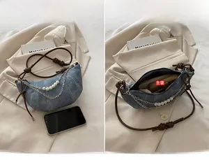 Detail of blue denim crescent bag with pearl chain and adjustable brown leather strap