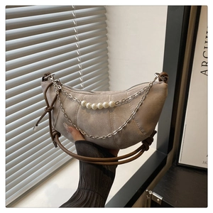 Detail of hobo bag with denim texture, pearl chain and brown leather rope handle