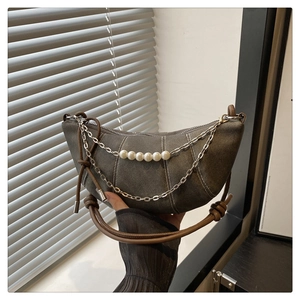 Detail of denim crescent bag featuring metal chains, large pearls and tassel pendant decoration