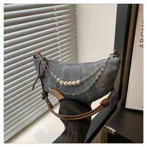 Detail of blue denim crescent bag with elegant pearl and silver chain decorations
