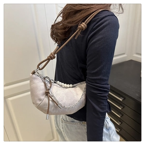 Detail of silver crescent bag with pearl chain and leather strap on model