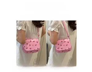 Detail showing pink cherry print handbag worn as a crossbody and shoulder bag