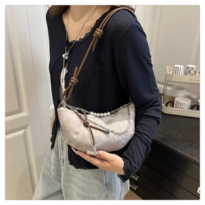 Détail du sac croissant gris clair avec bandoulière nouée et chaîne de perles décorative