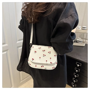 Detail shot of a white PU leather crossbody bag featuring a cute red cherry print pattern