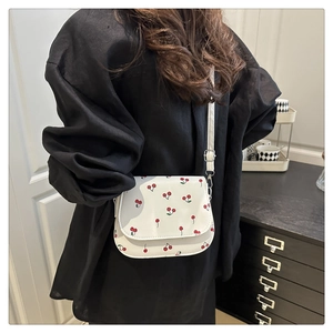 Detail of adjustable strap and metal buckle on white square bag with cherry print
