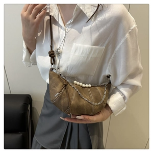 Détail d'un sac demi-lune marron orné de grosses perles et d'une chaîne argentée