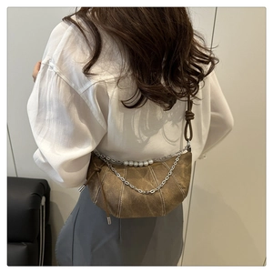 Détail du sac croissant marron foncé avec coutures blanches et chaîne de perles