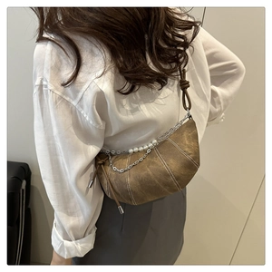 Detail of brown croissant bag with silver chain, white pearls and contrast stitching